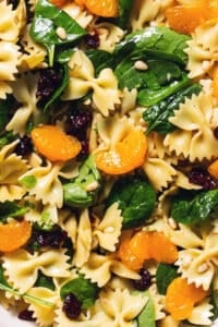 up close spinach, mandarin oranges, bowtie pasta noodles, and craisins