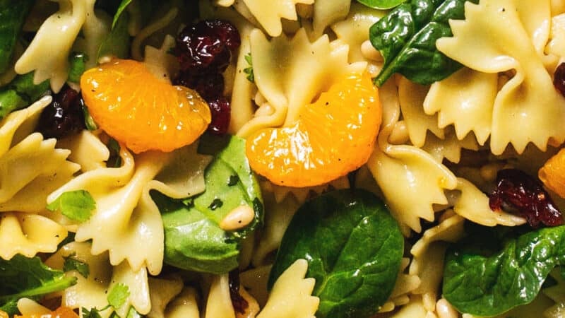 up close spinach, mandarin oranges, bowtie pasta noodles, and craisins