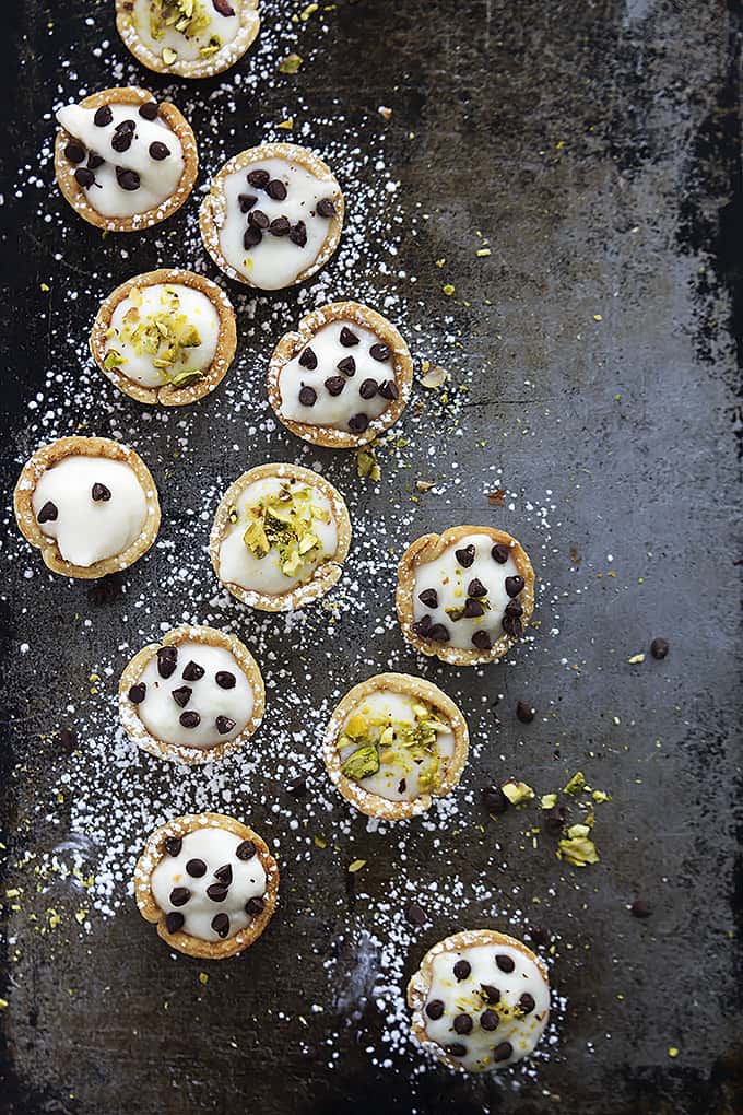 top view of cannoli bites topped with powdered sugar and chocolate chips or pistachios.