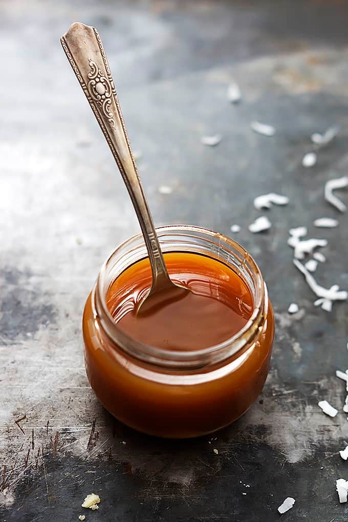 a small jar of caramel with a spoon in it.