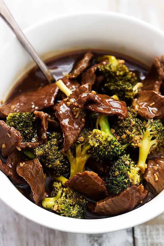close up of slow cooker broccoli beef and a spoon in a bowl.