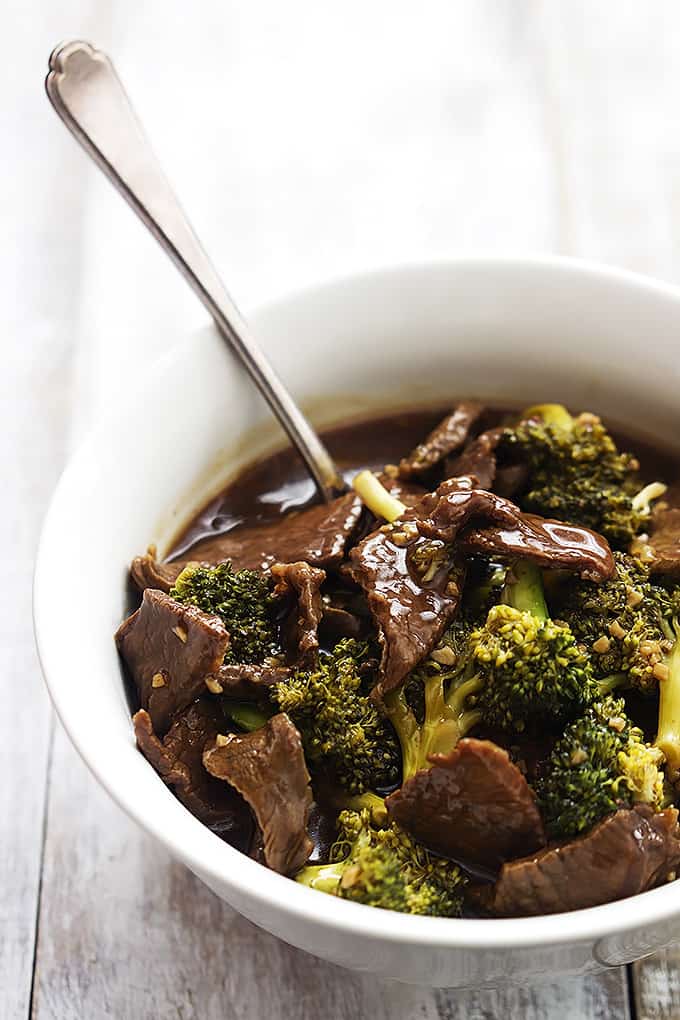 slow cooker broccoli beef and a spoon in a bowl.