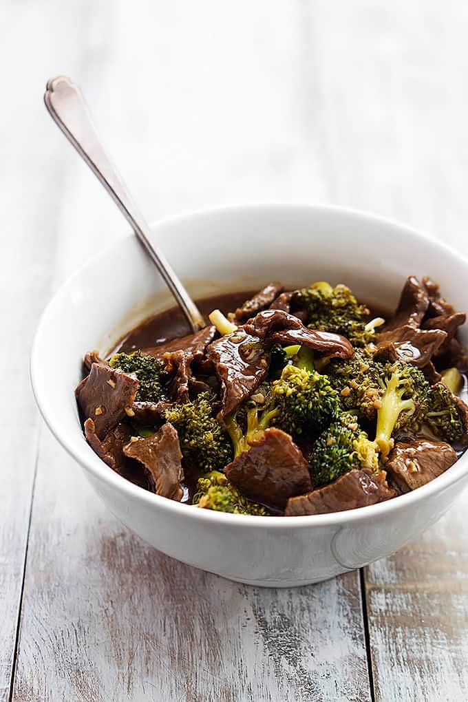 slow cooker broccoli beef and a spoon in a bowl.