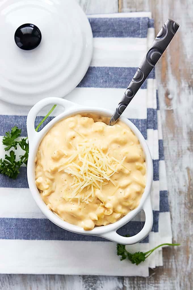 top view of slow cooker 4 cheese macaroni with a spoon in a bowl with a lid on the side.