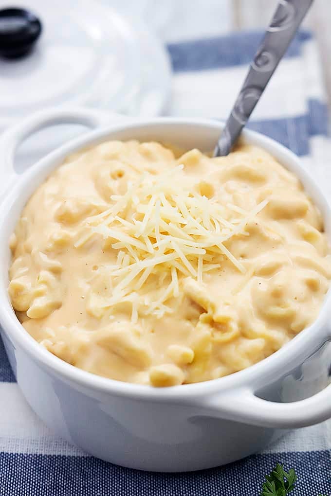 slow cooker 4 cheese macaroni with a spoon in a bowl.