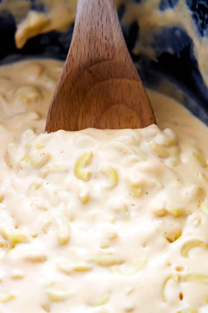 close up of slow cooker 4 cheese macaroni  and a wooden spoon in a slow cooker.