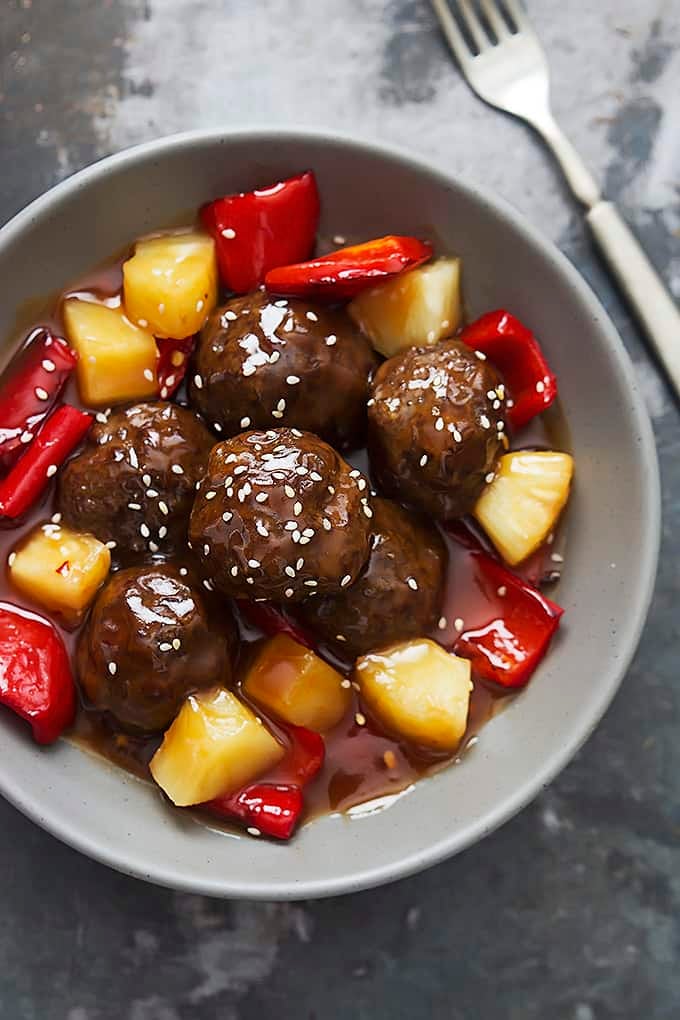 top view of slow cooker sweet & sour meatballs in a bowl with a fork on the side.