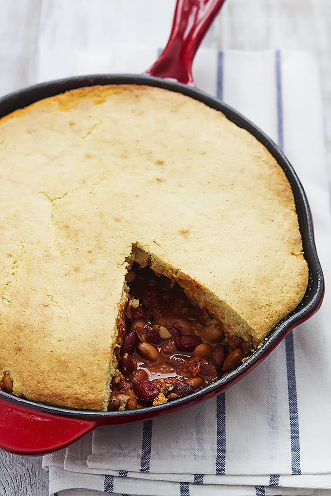 Chili cornbread skillet pie in a skillet with a slice missing.