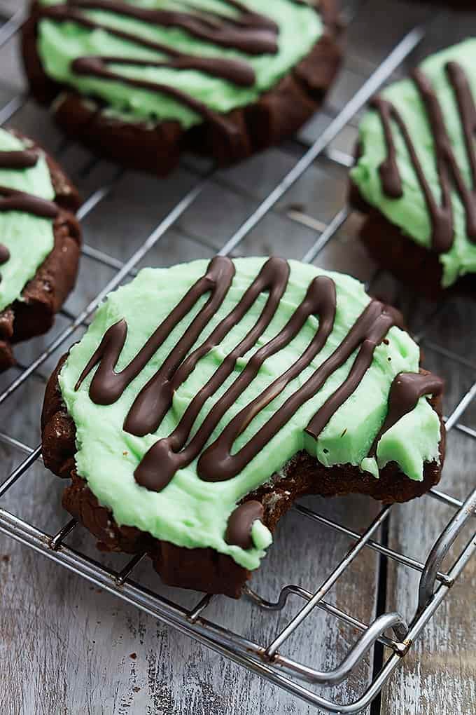 a grasshopper sugar cookie with a bite taken out of it with more cookies on the side all on a cooling rack.