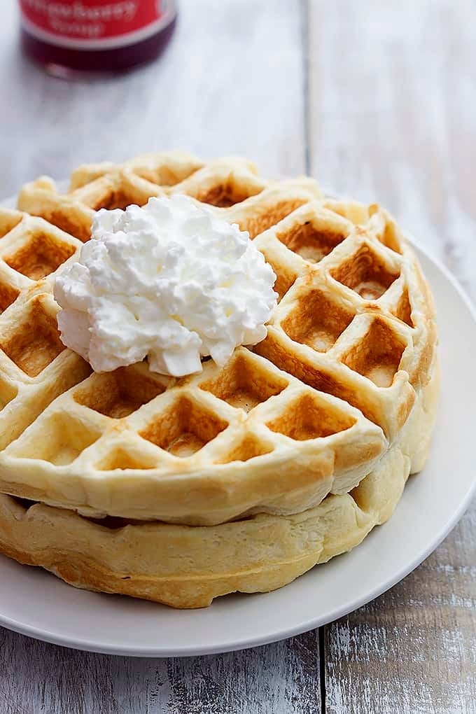 Greek yogurt waffles topped with whipped cream on a plate..