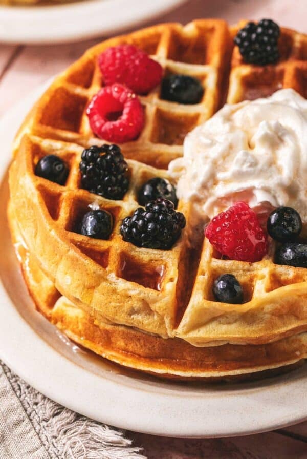 Close up of a greek yogurt waffles with berries and cream on a plate.
