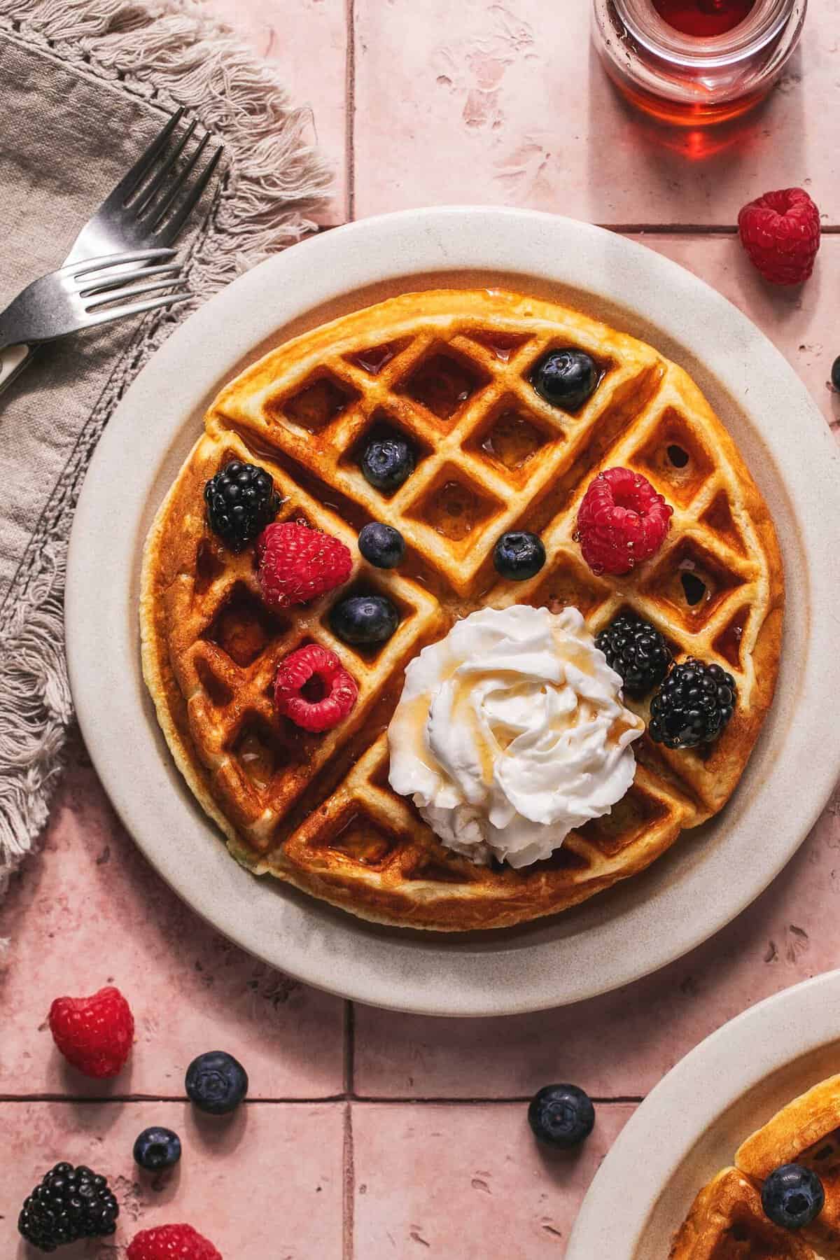 Overhead of a greek yogurt waffles with berries and cream on a plate.