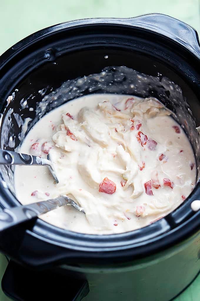 slow cooker chicken quesadillas filling with serving spoons in a slow cooker.