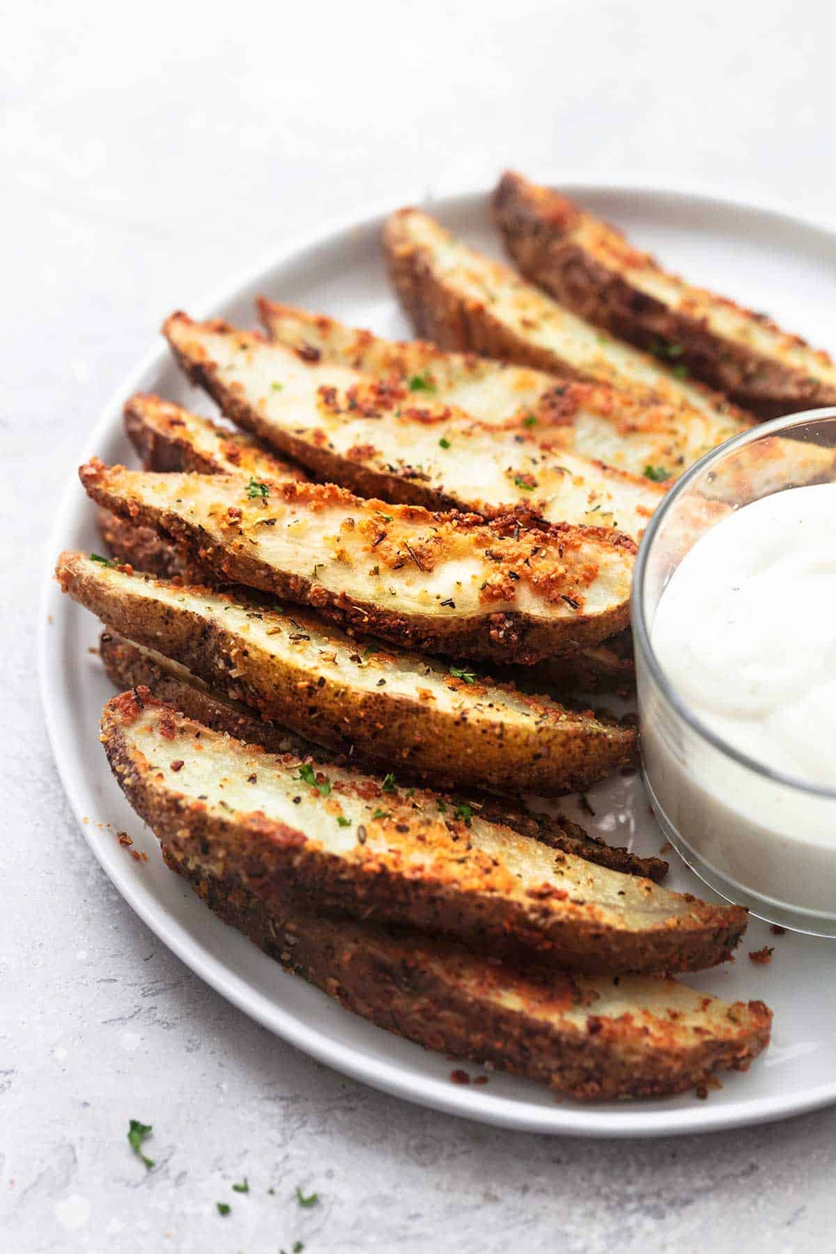 cuñas de patata al horno con rancho en plato blanco