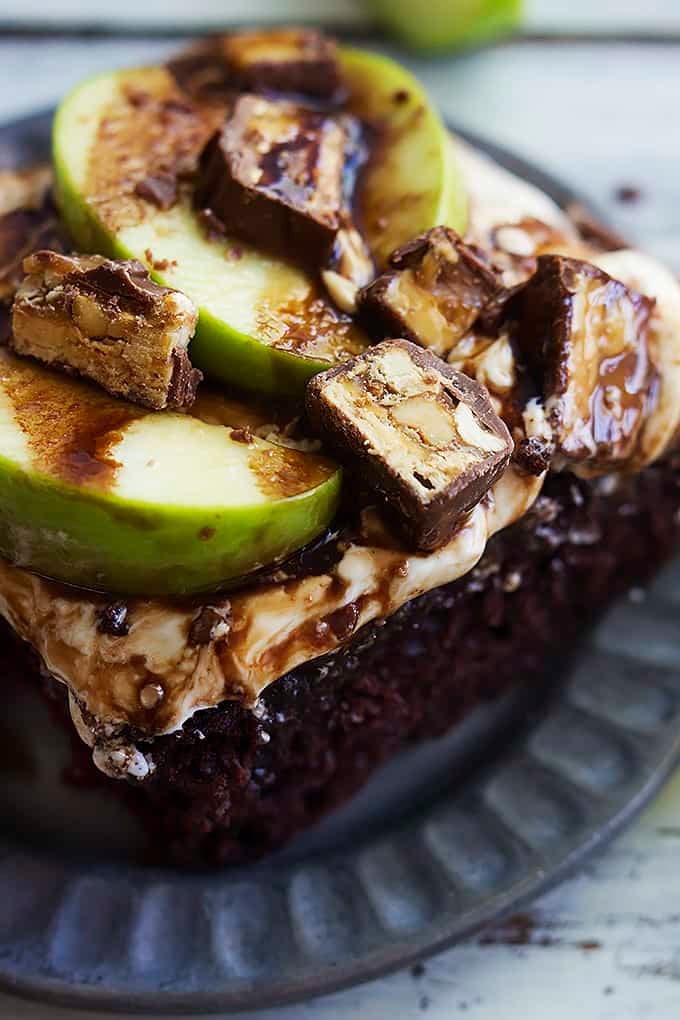 close up of a slice of caramel apple snickers cake on a plate.