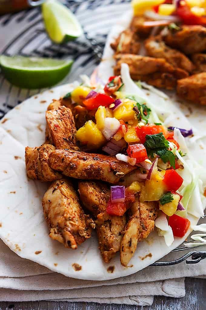 a Caribbean chicken taco with another taco and lime slices in the background.