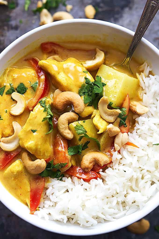 top view of slow cooker coconut curry cashew chicken and rice with a spoon in a bowl.