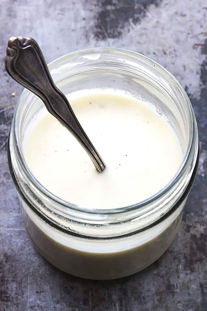 Greek yogurt alfredo sauce in a jar with a spoon inside.