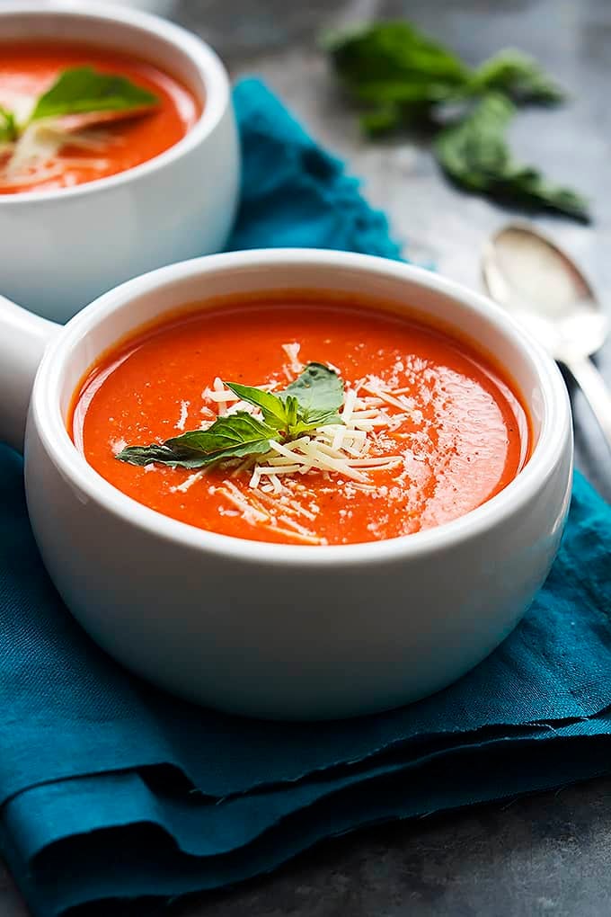 roasted red pepper soup in a bowl with a spoon and another bowl of soup on the side.