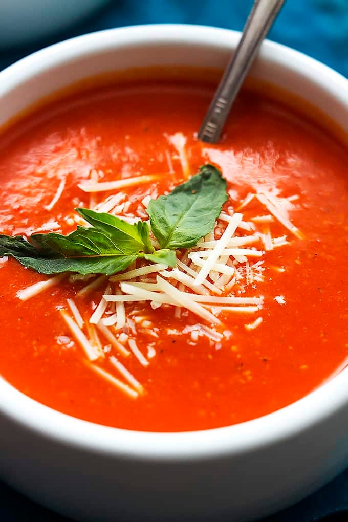 close up of roasted red pepper soup and a spoon in a bowl.