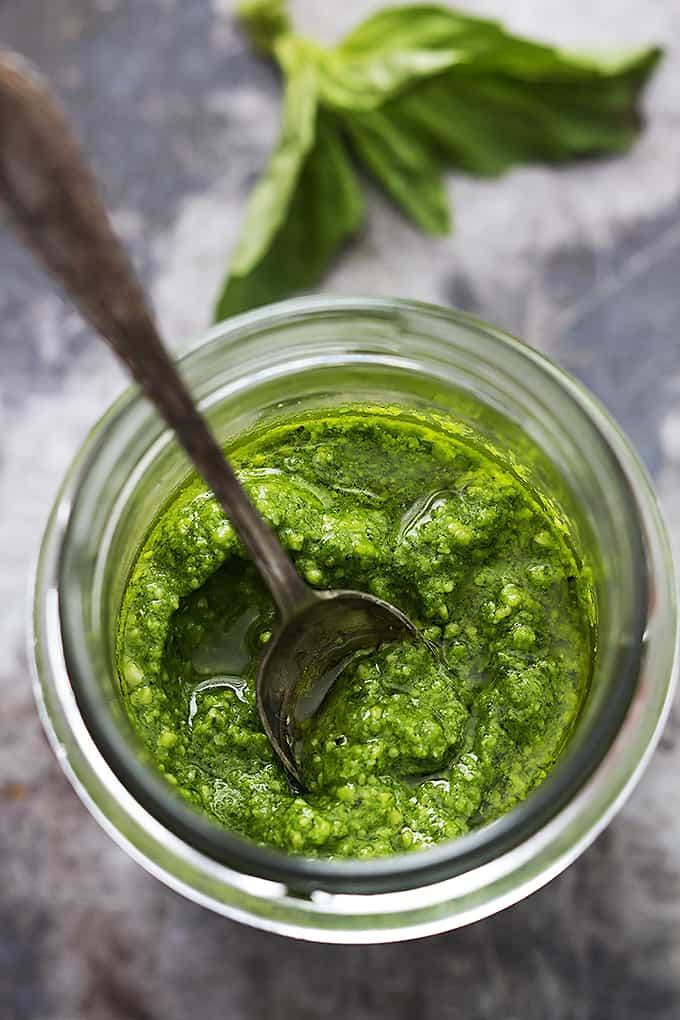 top view of a jar of pesto with a spoon inside.