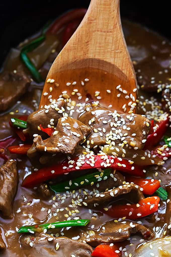 close up of slow cooker sesame beef and wooden spoon.