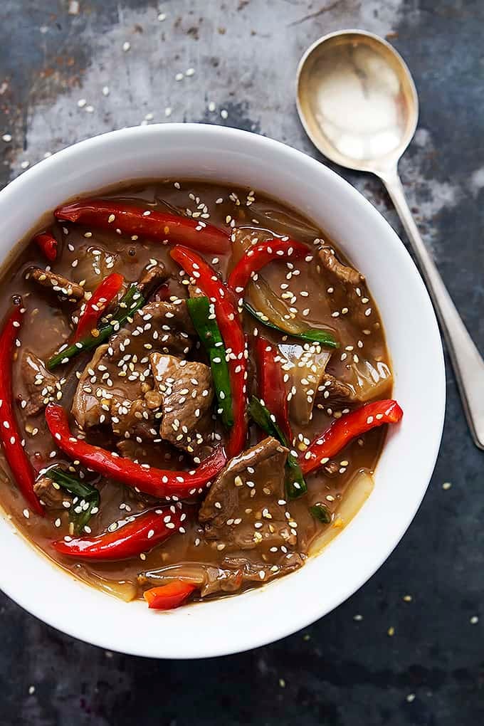 top view of slow cooker sesame beef in a bowl with a spoon on the side.