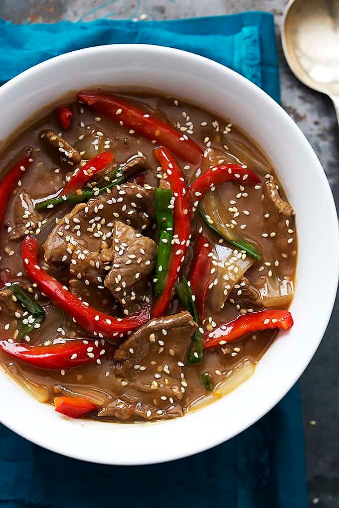 top view of slow cooker sesame beef in a bowl with a spoon on the side.