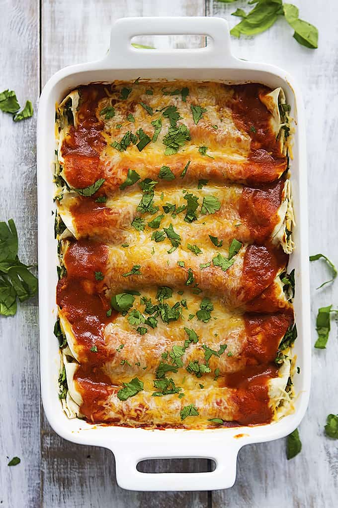top view of cheesy spinach enchiladas in a baking pan.