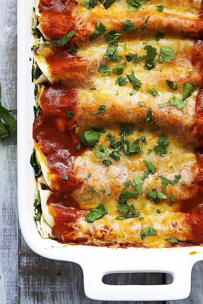 close up top view of cheesy spinach enchiladas in a cooking pan.
