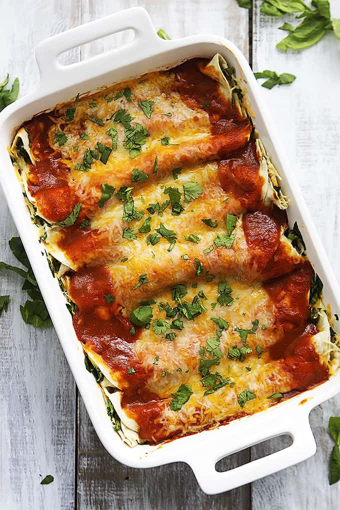top view of cheesy spinach enchiladas in a baking pan.