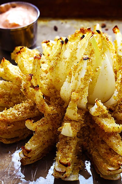 baked blooming onion with fry sauce in a dipping bowl in the background.