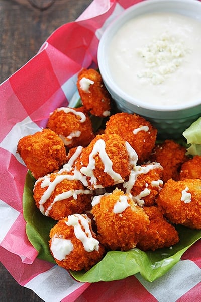 baked buffalo popcorn chicken with dipping sauce on the side in a serving basket.