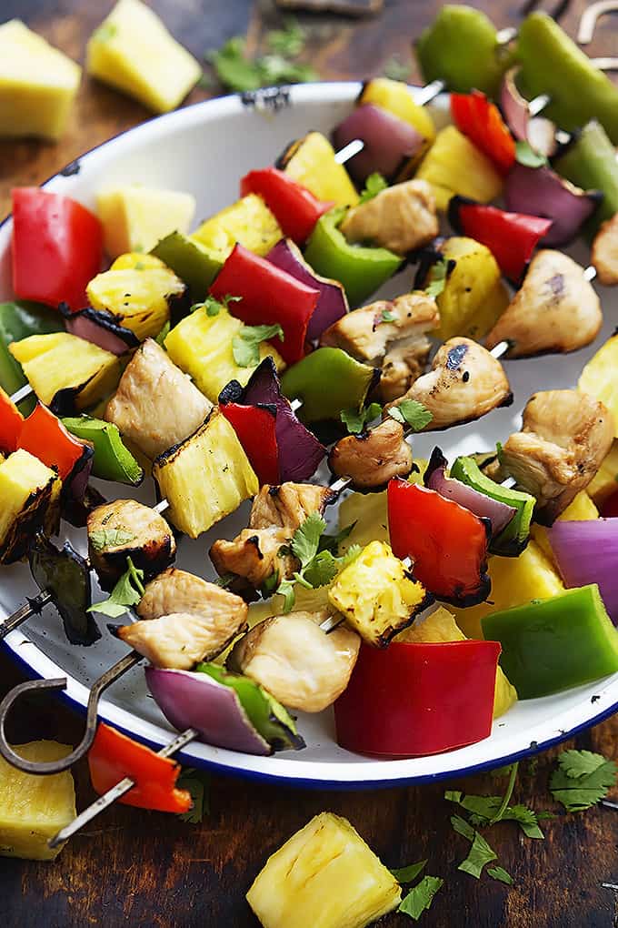grilled Hawaiian chicken kabobs laying across a bowl.