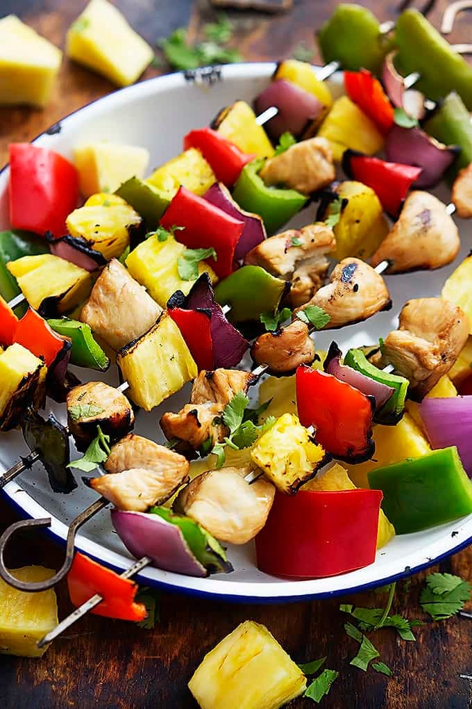 grilled Hawaiian chicken kabobs laying across a bowl.