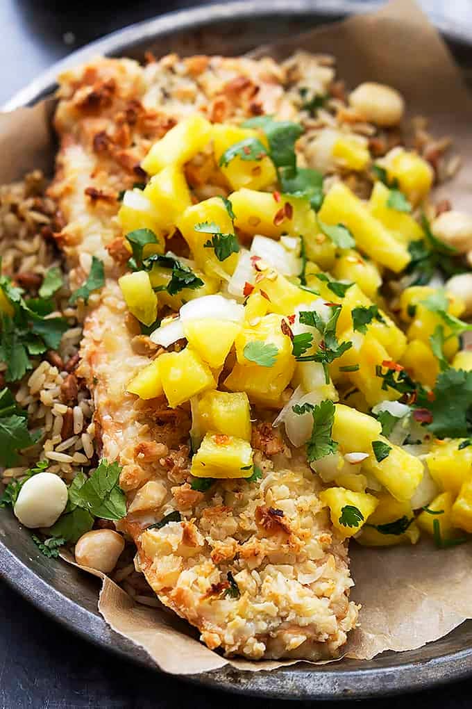 close up of macadamia salmon with pineapple salsa on a round metal plate.