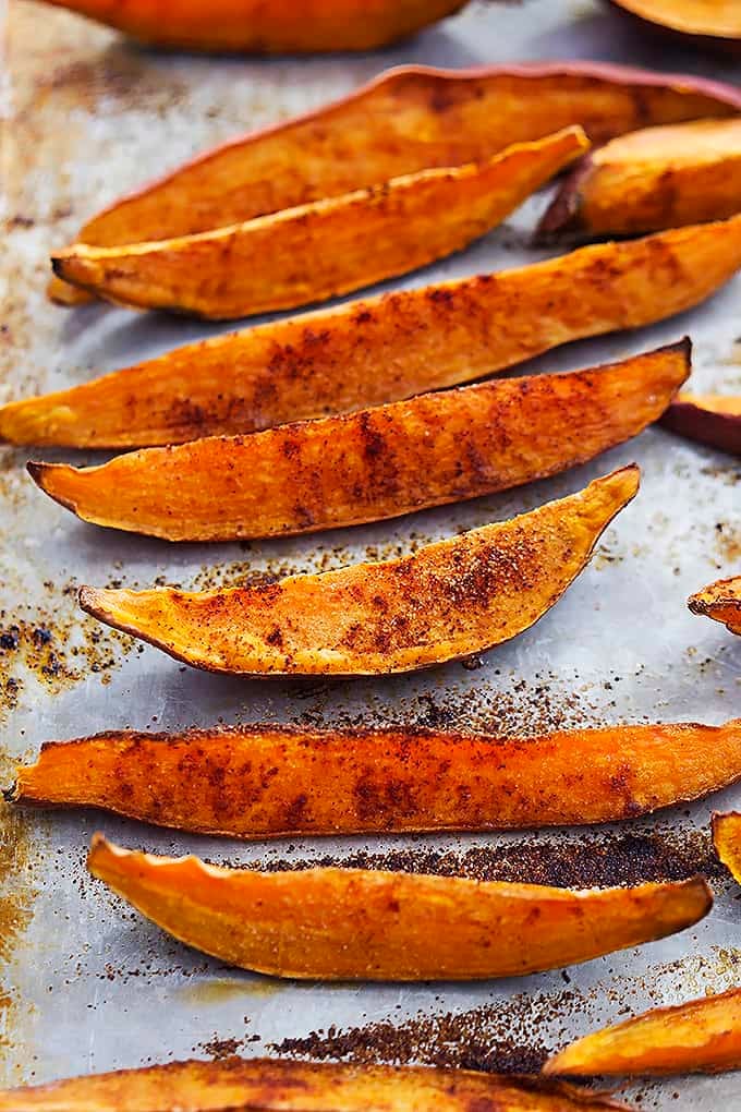 close up of spicy baked sweet potato wedges on a baking sheet.