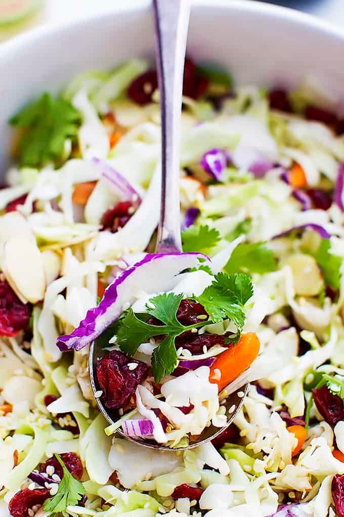 close up of a spoon scooping some Asian cranberry almond salad from a bowl.