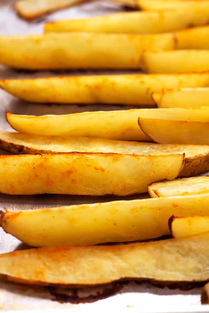 close up of baked garlic sriracha fries on a baking sheet.