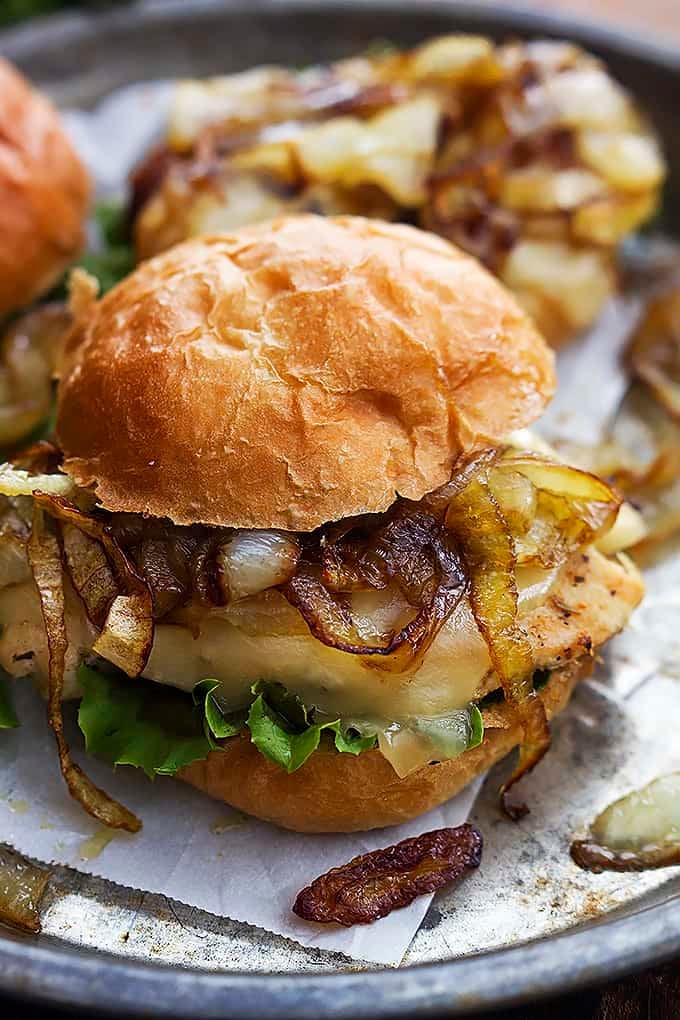 a French onion chicken slider with onions and another slider on a round serving tray.
