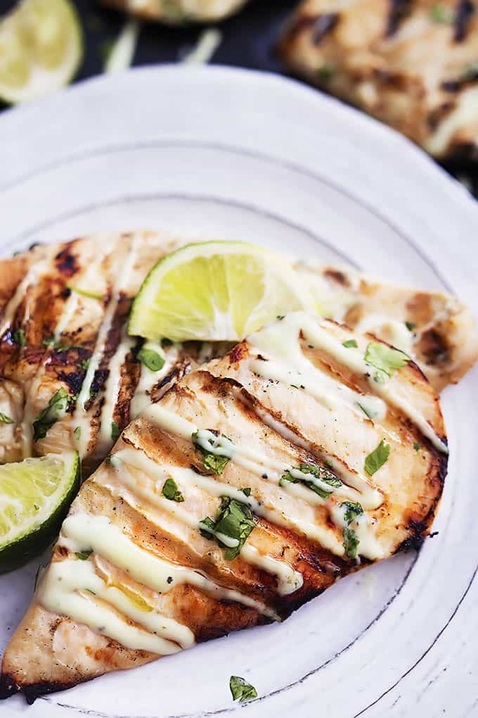 grilled cilantro lime chicken with lime slices on a plate.