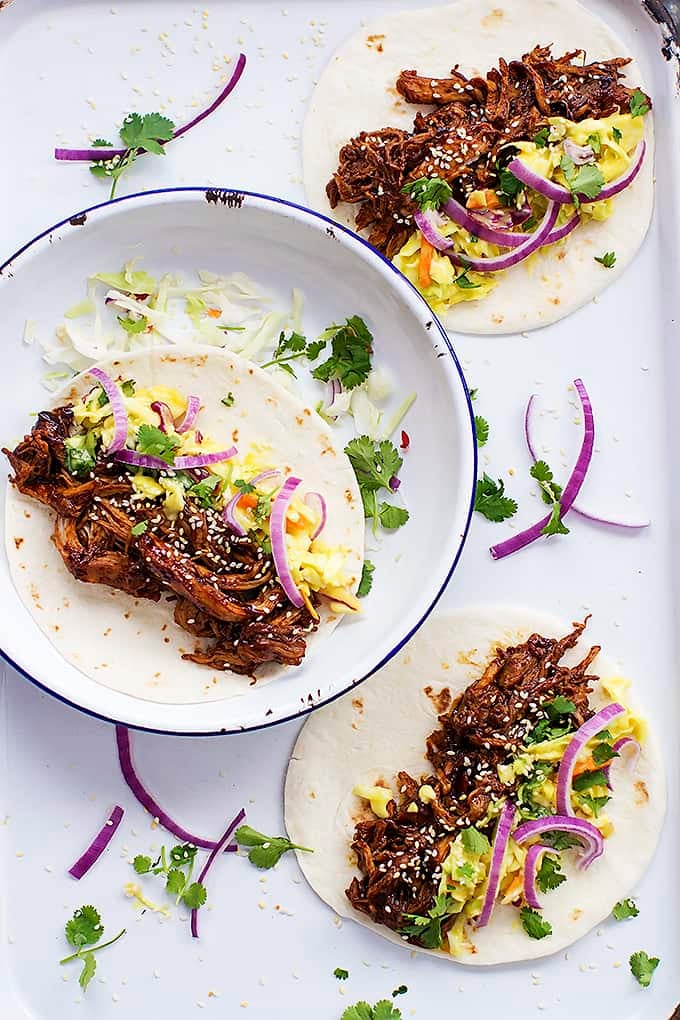 top view of a slow cooker Korean bbq pork taco on a plate with more tacos on the side.