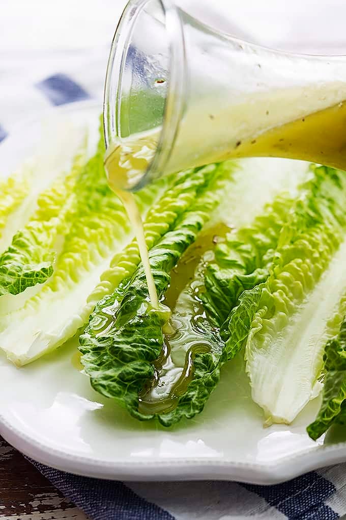 romaine finger salad on a plate with Italian dressing being poured on top.