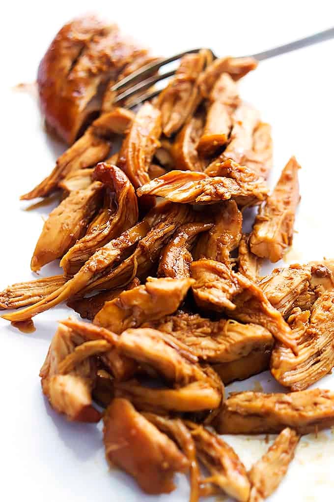 a fork shredding up slow cooker honey garlic chicken.