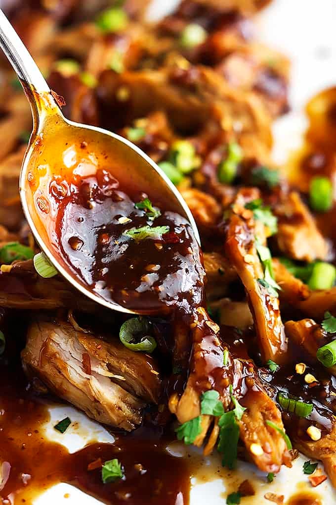 sweet and spicy Asian garlic sauce being poured on top of slow cooker honey garlic chicken with a spoon.
