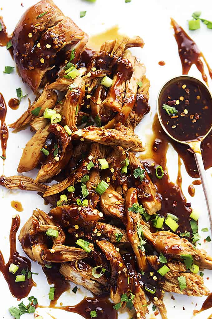 top view of slow cooker honey garlic chicken with a spoon of sweet and spicy Asian garlic sauce on the side.