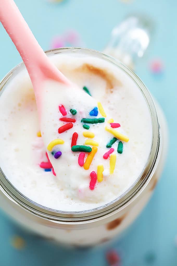 top view of a pink spoon being lifted from a mason jar of cake batter smoothie.