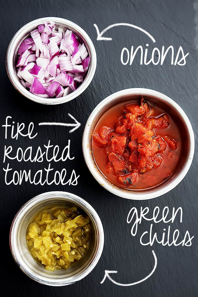 top view of three bowls of onions, tomatoes, and green chiles with the title of the ingredients written on the image with arrows pointing to the bowls.