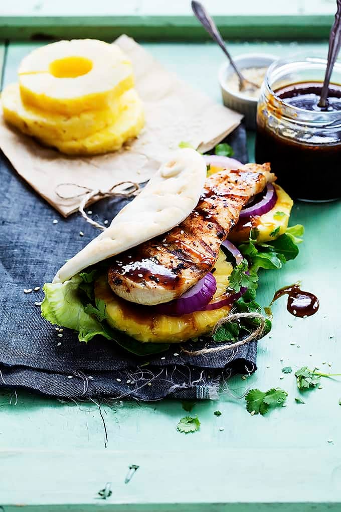 a grilled pineapple teriyaki chicken wrap with pineapple slices and a jar of sauce in the background.