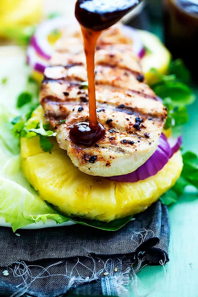 close up of an open grilled pineapple teriyaki chicken wrap with sauce being poured on top.